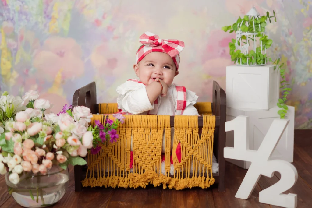 Baby girl smiling in a woven basket during photoshoot in Ahmedabad.