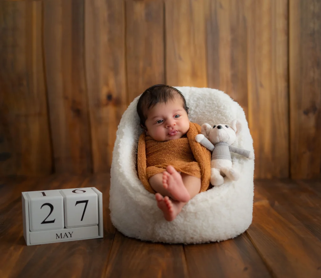 Baby photoshoot with plush toys in a cozy Ahmedabad studio setting.