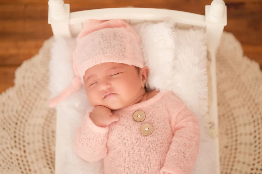 Newborn in pink outfit sleeping peacefully during a newborn photoshoot in Ahmedabad, capturing the essence of innocence.