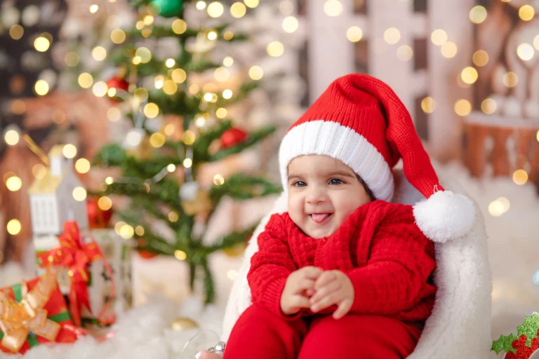 Newborn celebrating their first Christmas, cozy in a Santa hat, with twinkling lights in the background.