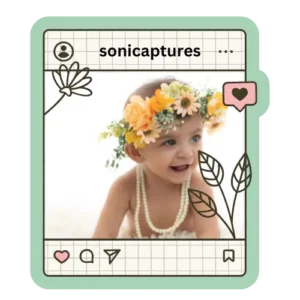 A cheerful baby wearing a floral headband and a string of pearls, beaming with joy in a stylized photo frame decorated with doodled flowers and a heart icon.